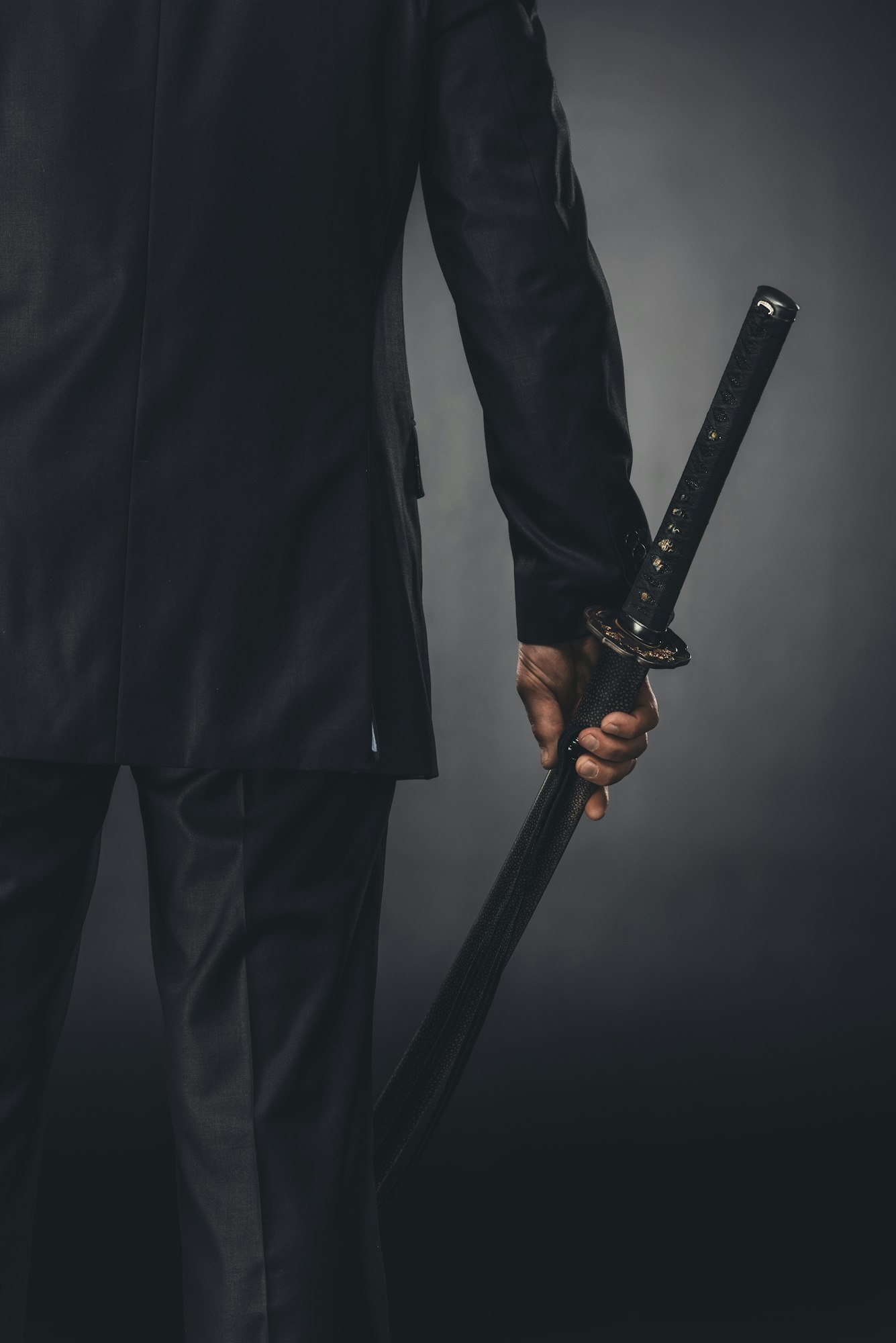 cropped shot of man in business suit with katana sword on black